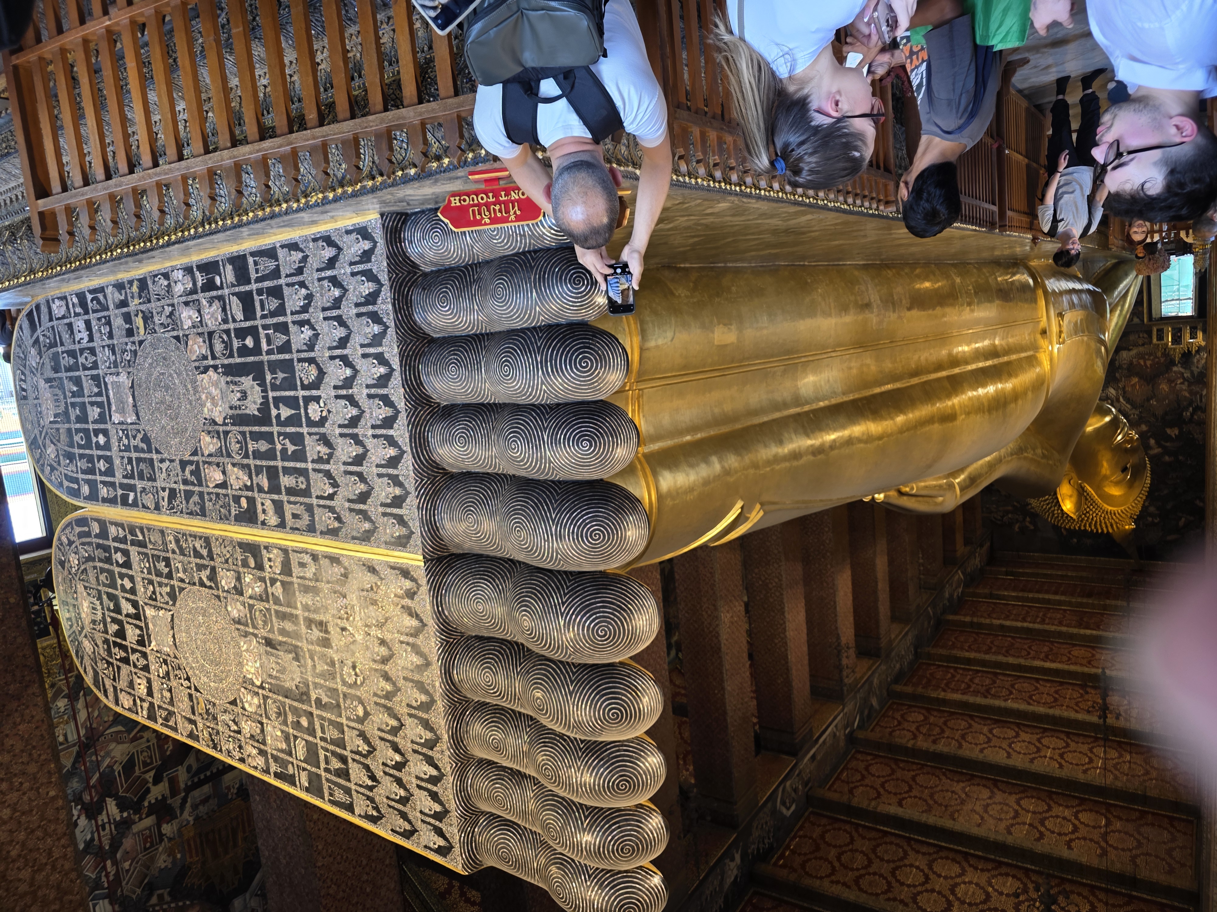 wide shot of Reclining Buddha's feet, mother-of-pearl inlay, crowd below