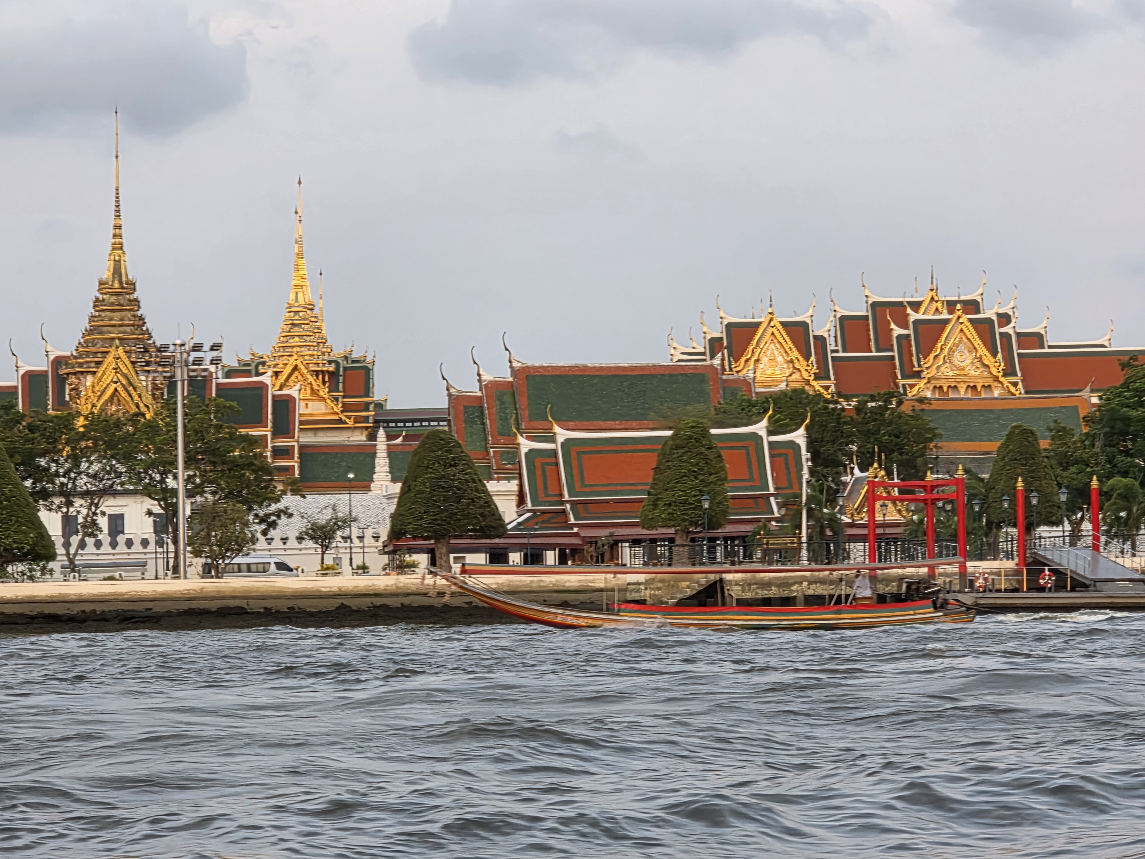Grand Palace skyline from the Chao Phraya, longtail boat in foreground