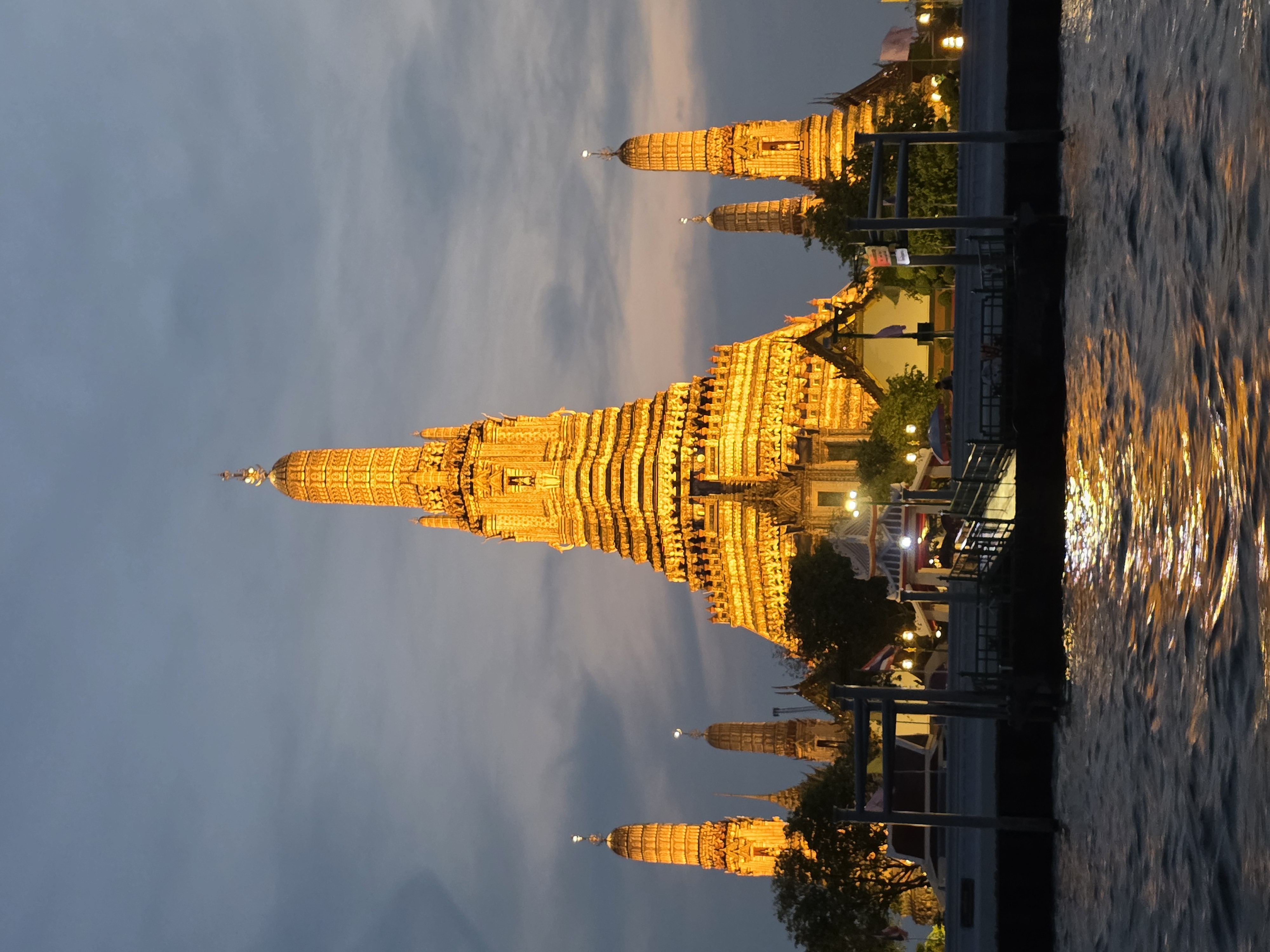 Wat Arun lit gold at dusk, viewed from the river
