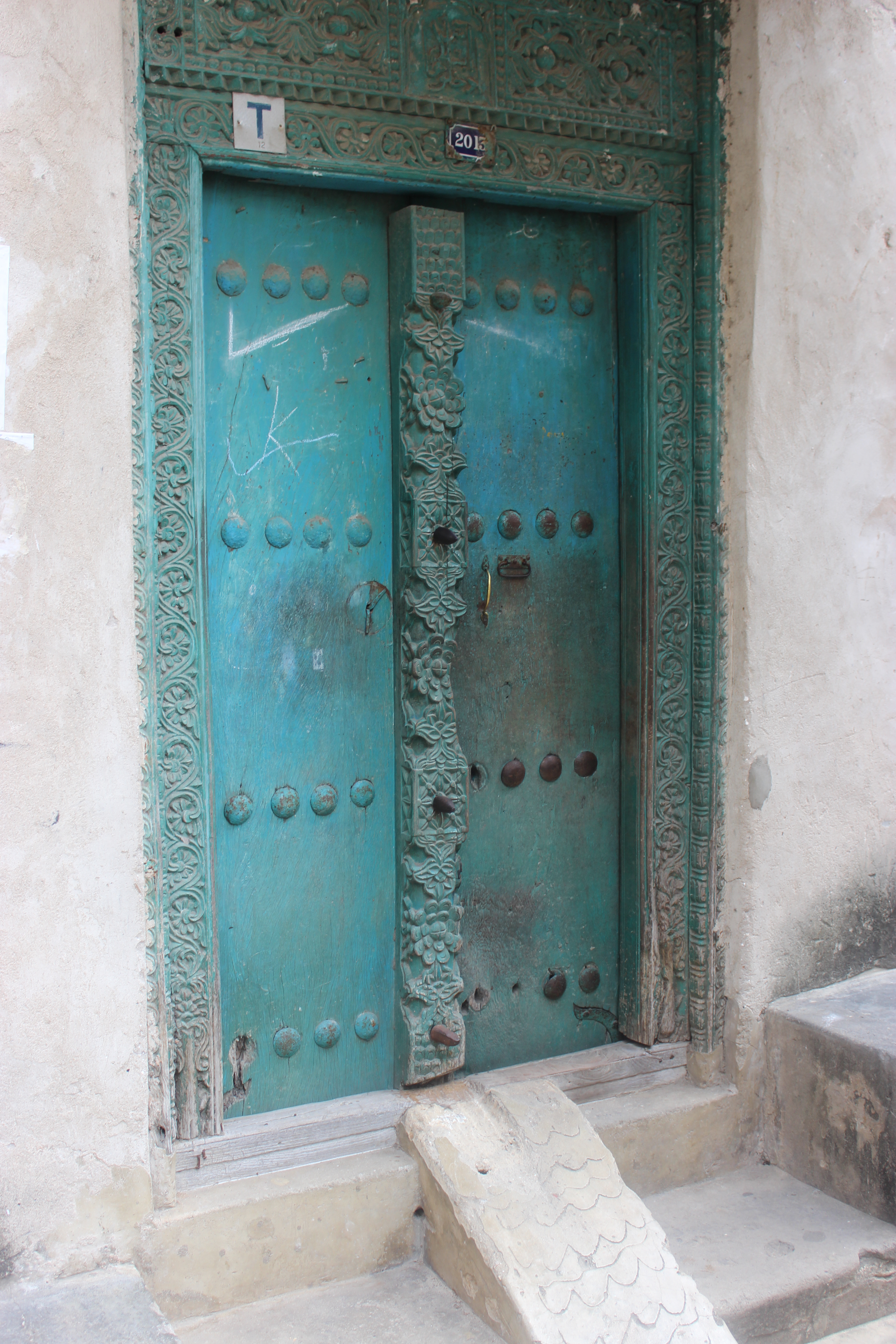 Iconic carved turquoise Stone Town door with brass studs and floral carving