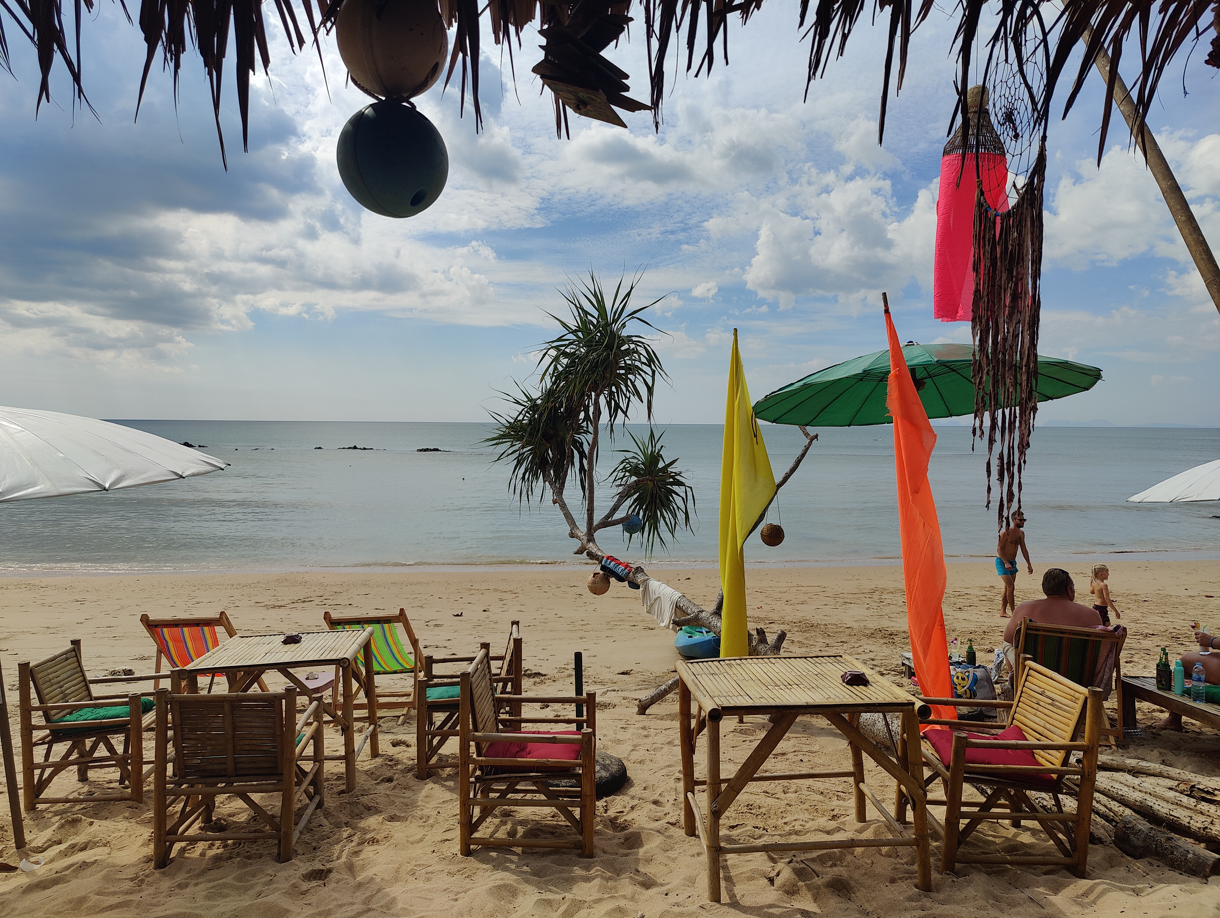 beach bar, bamboo tables, colourful flags, ocean beyond