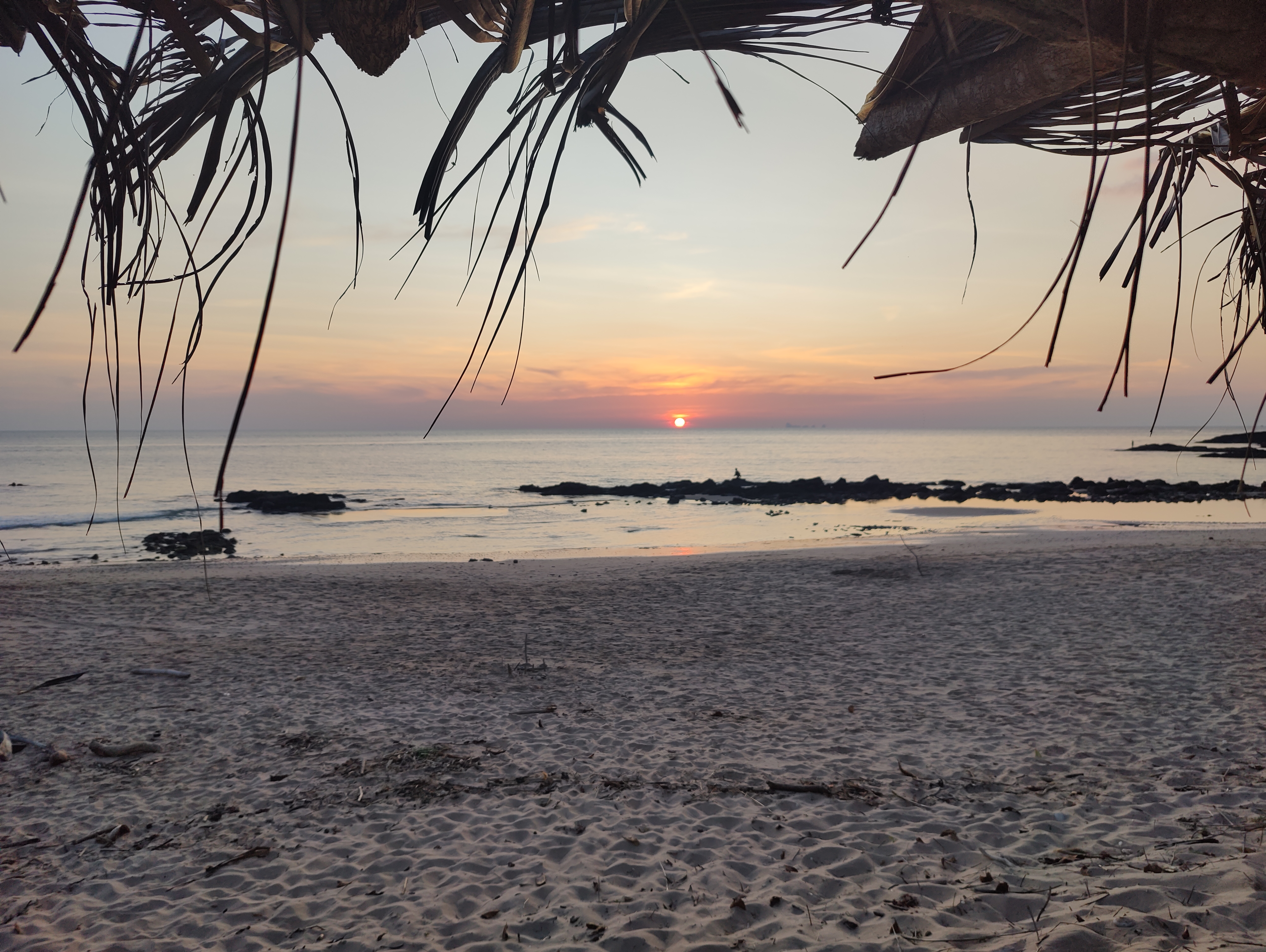 Koh Lanta sunset framed by palm thatch